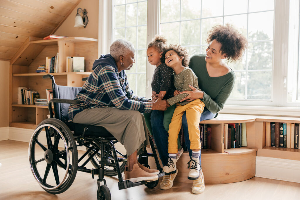 Adaptive housing: What Does it meant for your home. 3 Generation family sitting in a home, the oldest woman is in a wheelchair.