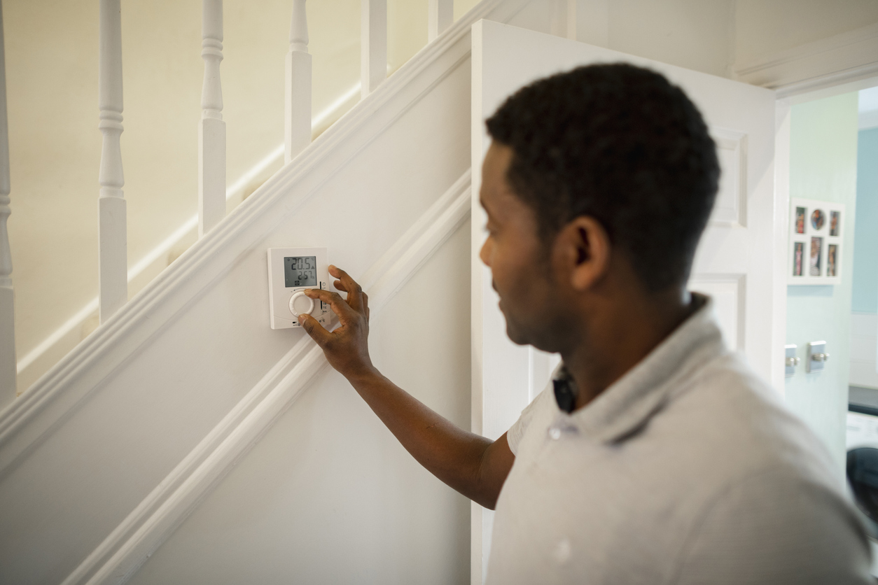 Man turning thermostat down