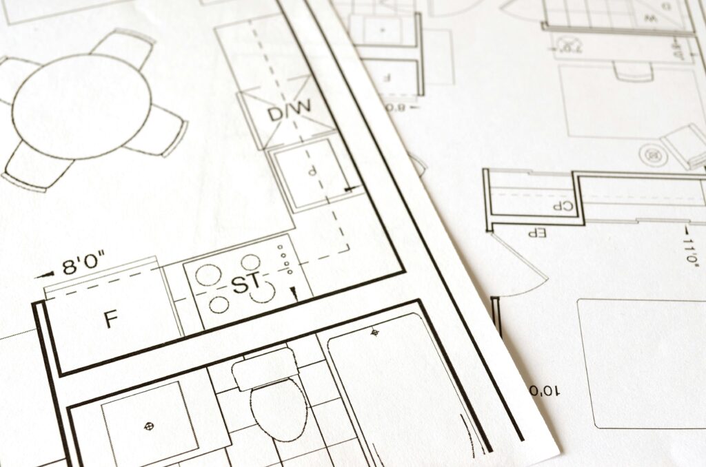 Architectural blueprints with floor plan drawings and measuring tools on a drafting table.
