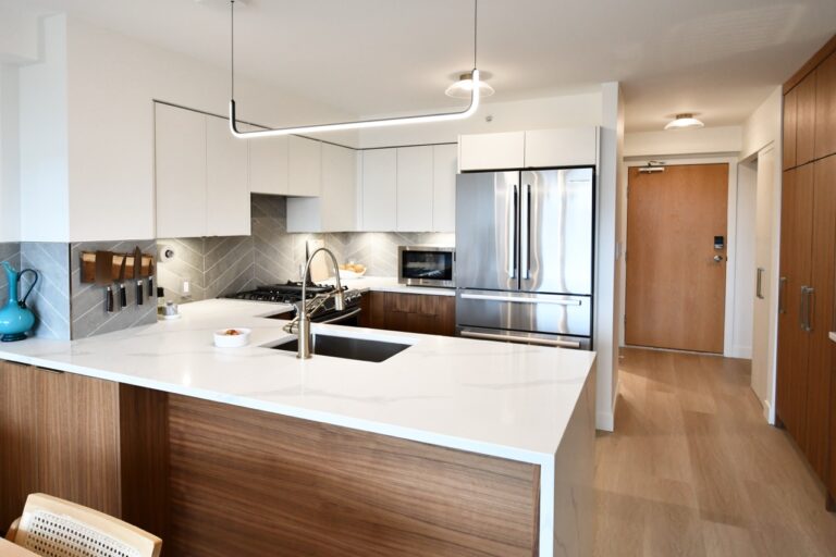 Condo kitchen with a quartz waterfall countertop and two-toned walnut and white cabinetry