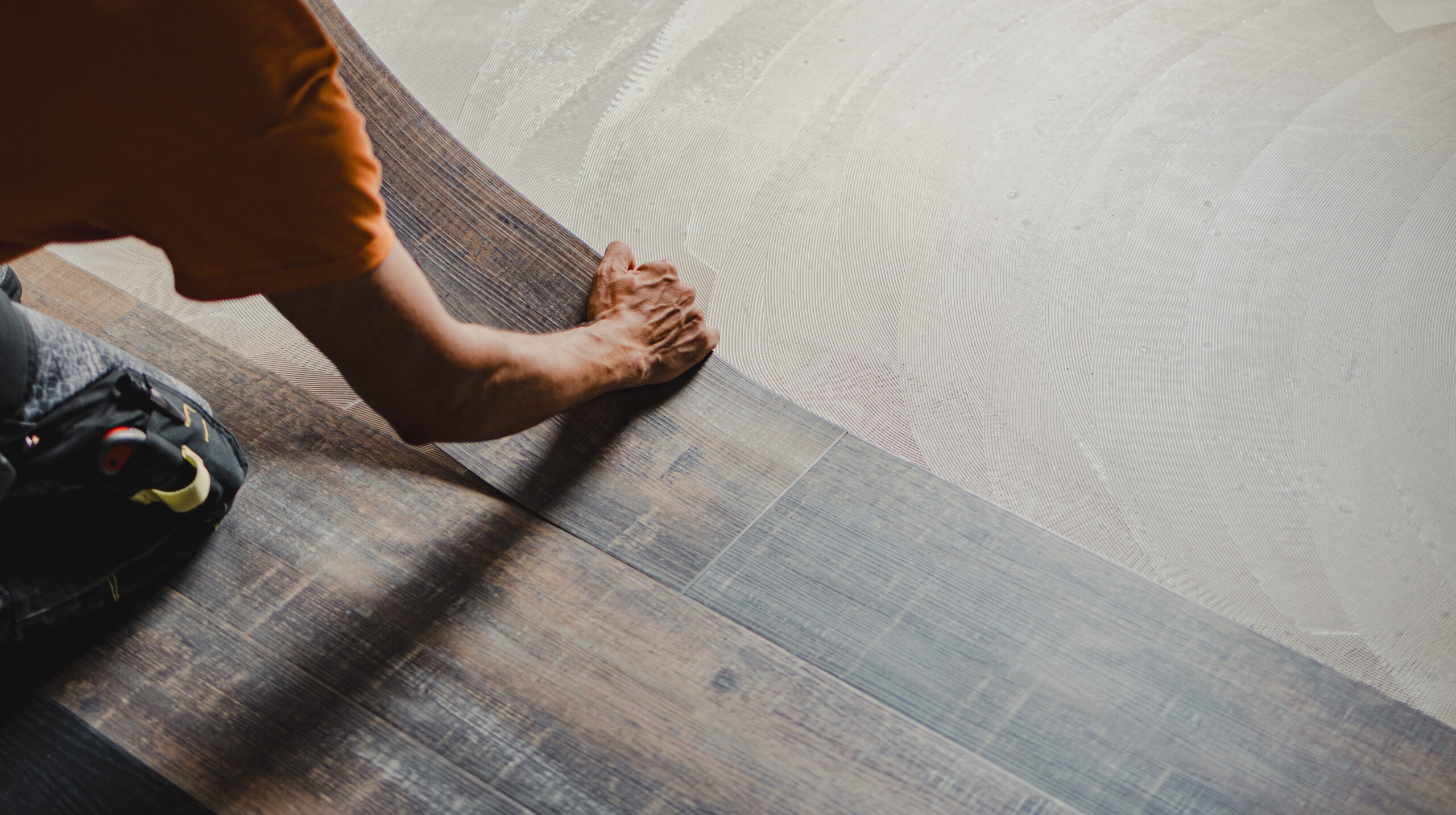 Installer fitting new vinyl plank flooring using the glue-down method