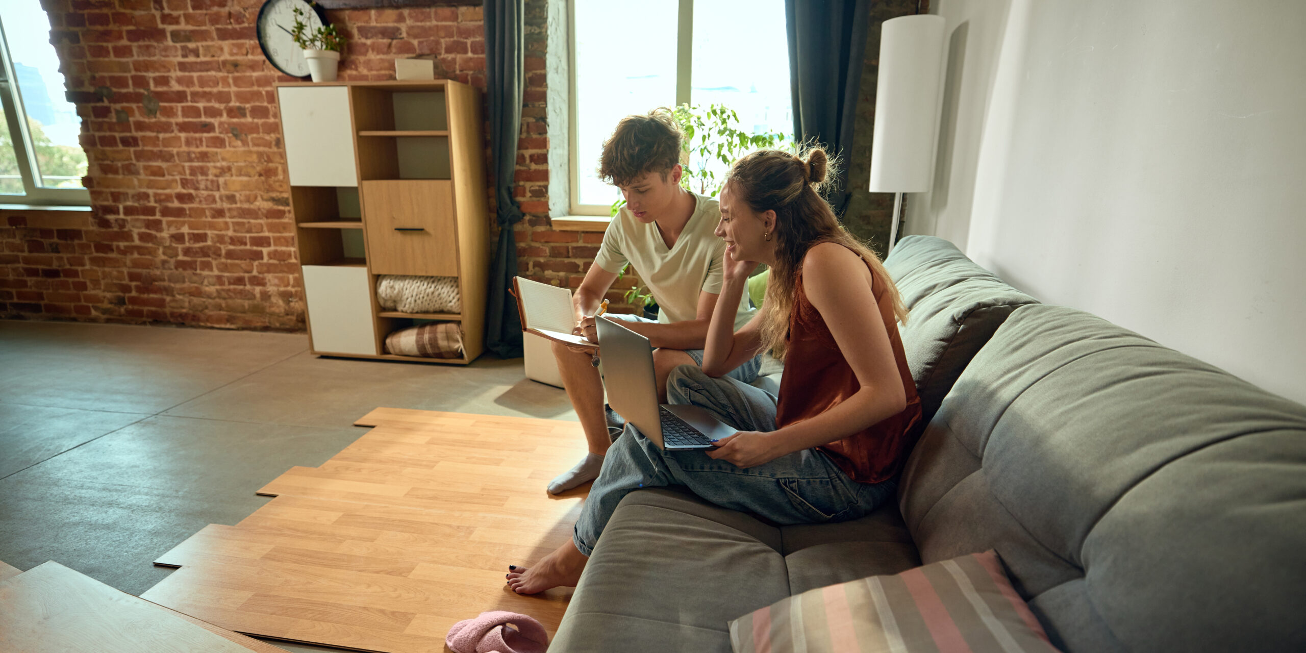 A couple comparing flooring and furniture options on a laptop at home