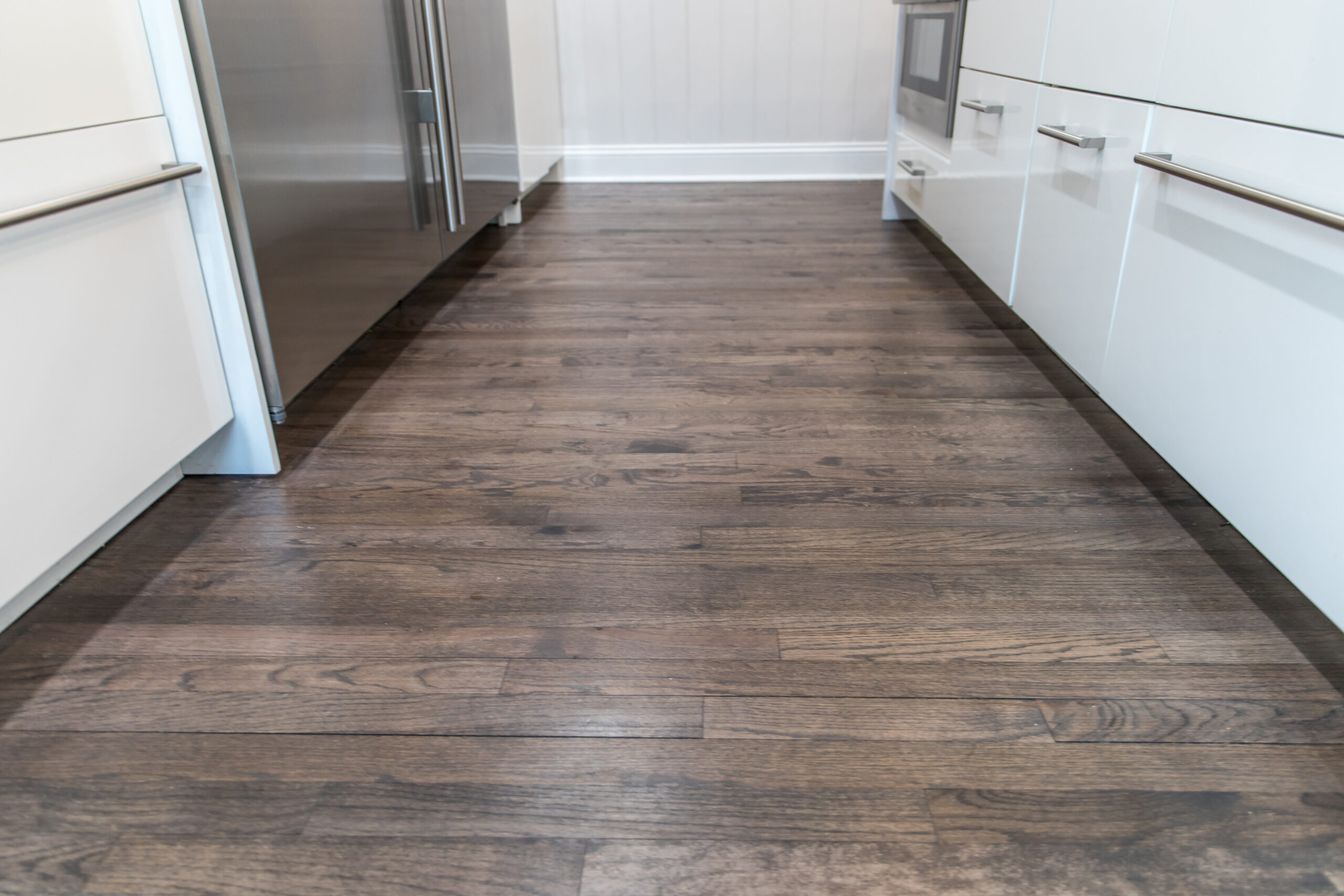 Dark wood-look plank flooring in a newly renovated white kitchen
